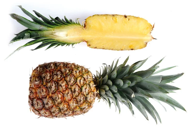 Celý zralý ananas s řezem ukazuje jeho vnitřní strukturu.
